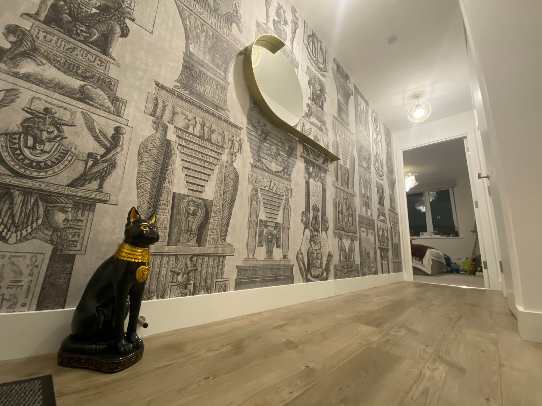 Egyptian engraving mural wallpaper running the full length of a hallway wall, matched around a doorway